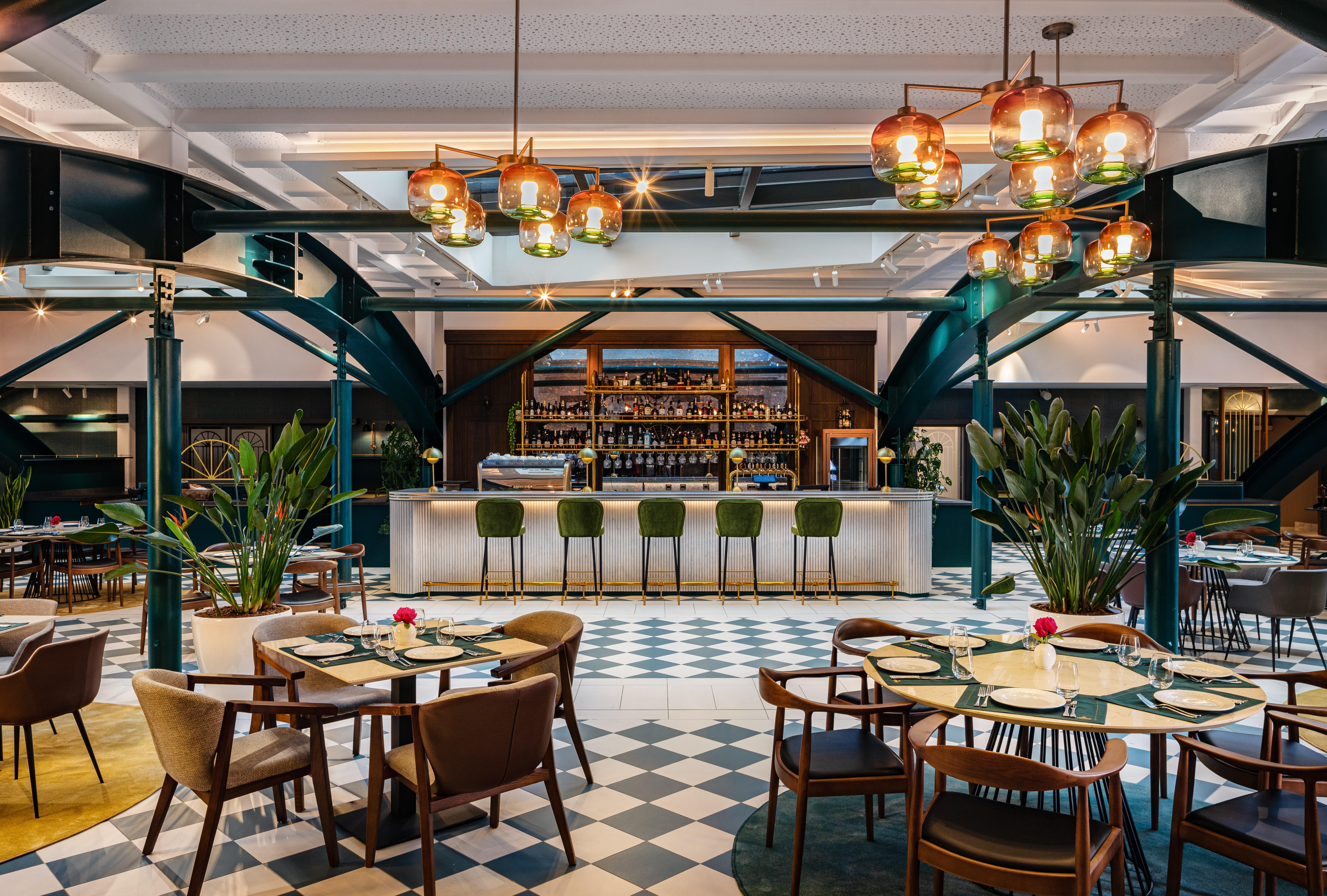 Grand Hotel Millennium Софія Екстер'єр фото The photo showcases a stylish restaurant interior. There are several tables set with chairs arranged around them, featuring a mix of styles. In the background, a sleek bar counter is visible, stocked with various bottles. The bar is complemented by e
