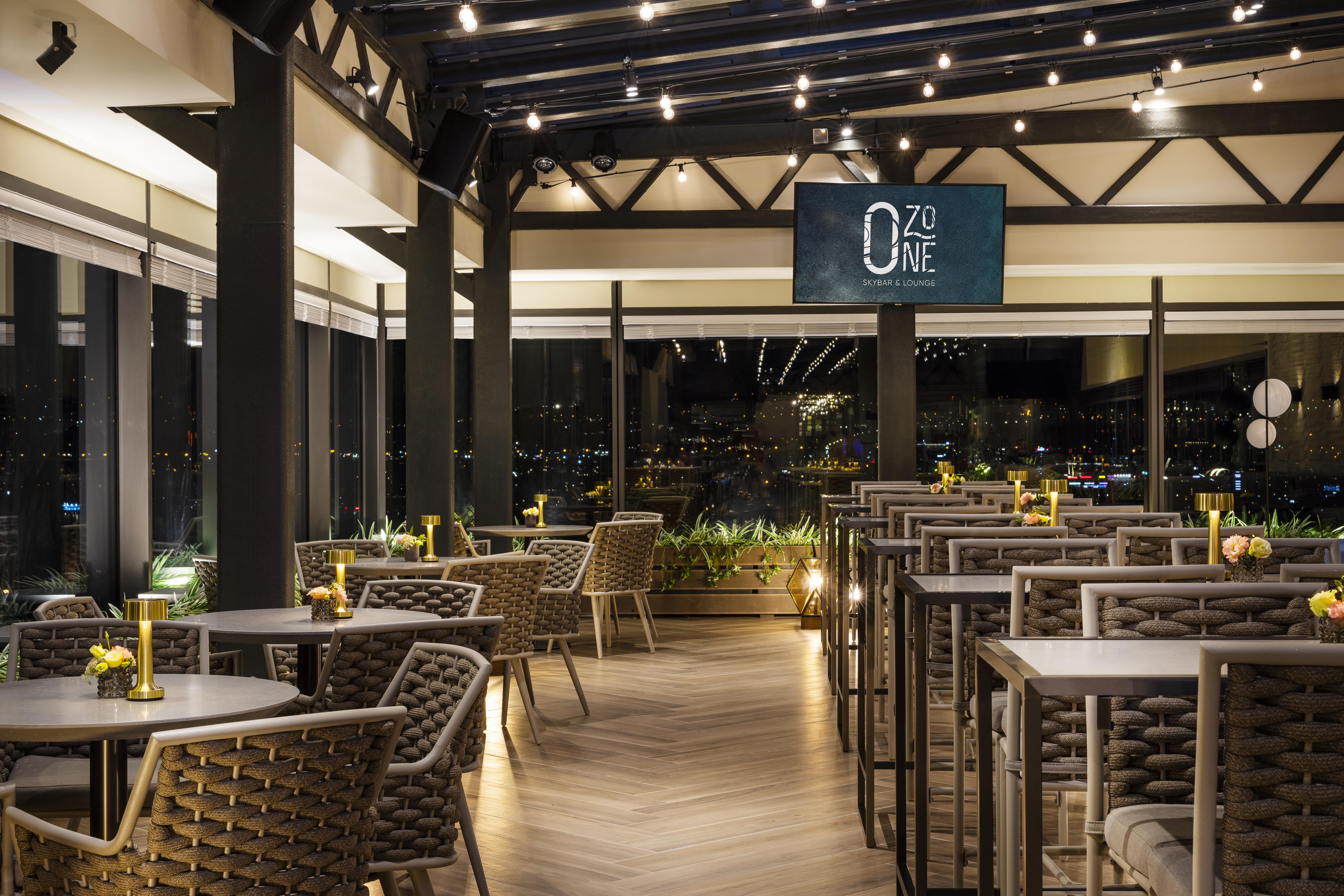Grand Hotel Millennium Софія Екстер'єр фото The photo depicts a modern restaurant interior with a stylish design. The space features a series of tables and chairs arranged neatly, with a clean and sophisticated aesthetic. The tables are set with small yellow flowers, adding a touch of color to